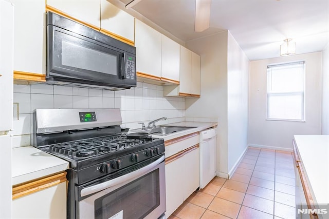 kitchen featuring white dishwasher, sink, light tile patterned flooring, white cabinetry, and stainless steel range with gas stovetop