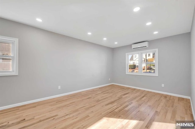 spare room with an AC wall unit and light hardwood / wood-style flooring