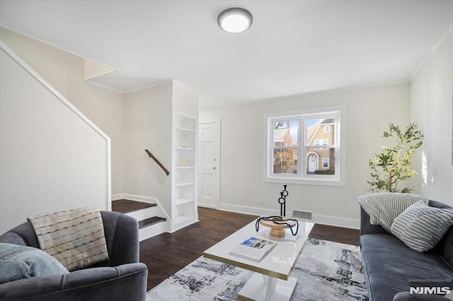 living room with dark wood-type flooring and crown molding