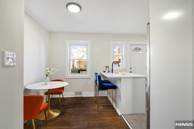 interior space with dark hardwood / wood-style floors, a breakfast bar area, and kitchen peninsula