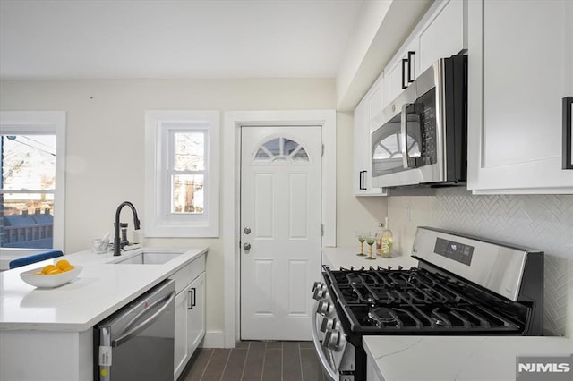 kitchen featuring stainless steel appliances, backsplash, light stone countertops, white cabinets, and sink