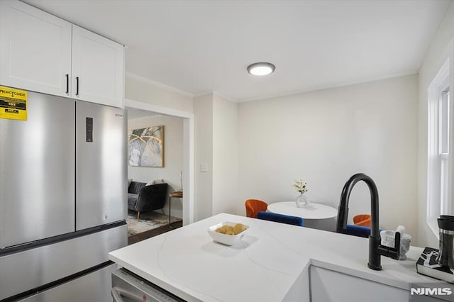 kitchen featuring white cabinets, stainless steel fridge, and sink