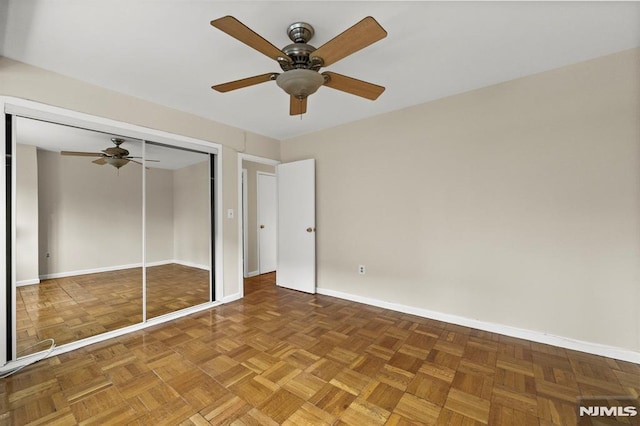 unfurnished bedroom with ceiling fan, dark parquet floors, and a closet