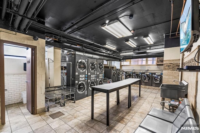 interior space featuring stacked washer / drying machine, a wealth of natural light, washer and dryer, and brick wall