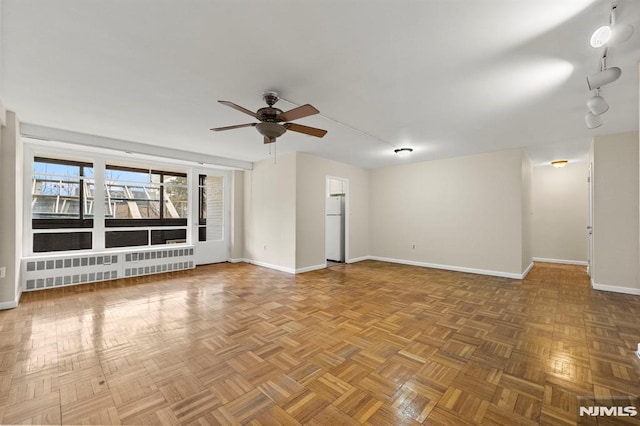 unfurnished living room with ceiling fan, parquet flooring, and radiator heating unit