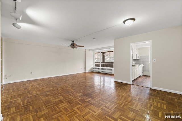 empty room featuring ceiling fan, radiator, and dark parquet floors