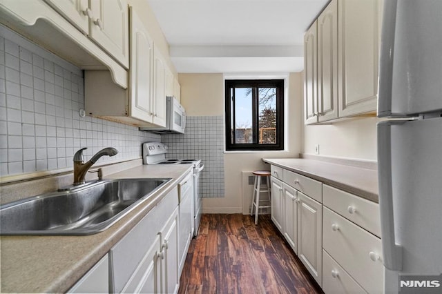 kitchen with sink, dark hardwood / wood-style floors, and white appliances