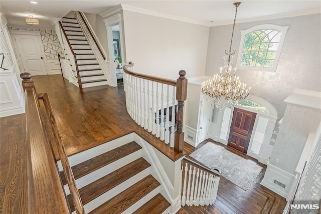 foyer entrance with a notable chandelier, ornamental molding, and dark wood-type flooring