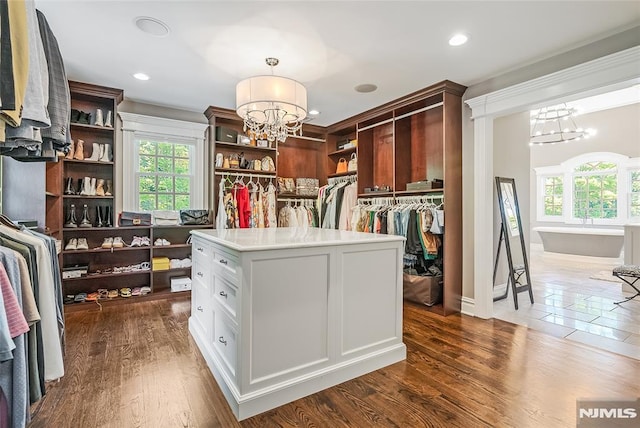 spacious closet featuring a notable chandelier and dark hardwood / wood-style flooring