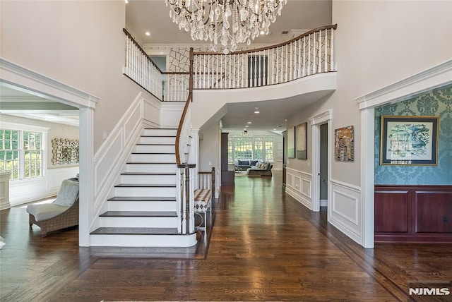 foyer featuring plenty of natural light, a towering ceiling, dark wood-type flooring, and a notable chandelier