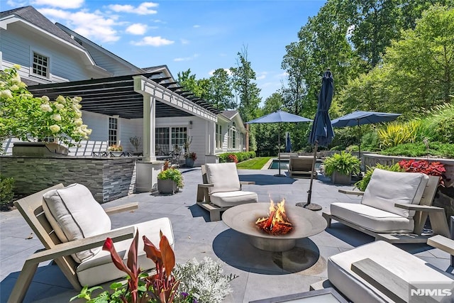 view of patio / terrace featuring exterior bar and an outdoor living space with a fire pit