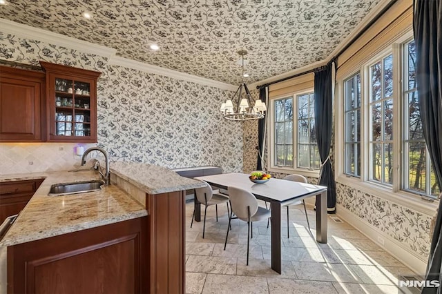 dining room with a notable chandelier, crown molding, and sink