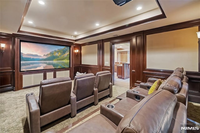 carpeted home theater room with crown molding and a tray ceiling