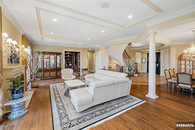 living room with decorative columns, dark wood-type flooring, ornamental molding, and an inviting chandelier