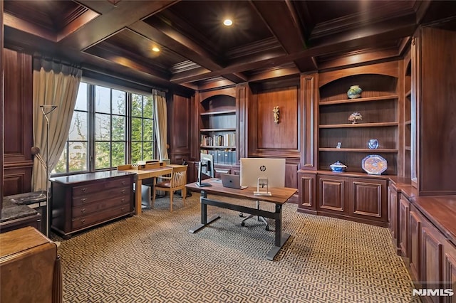 carpeted home office featuring crown molding, coffered ceiling, wooden walls, and built in shelves