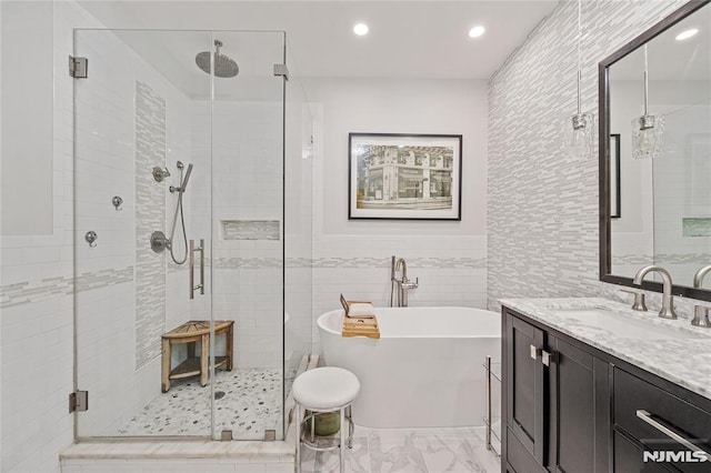 bathroom featuring vanity, separate shower and tub, and tile walls