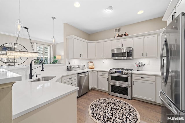 kitchen featuring white cabinets, decorative light fixtures, sink, and stainless steel appliances