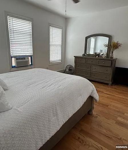 bedroom featuring ceiling fan, cooling unit, and hardwood / wood-style flooring