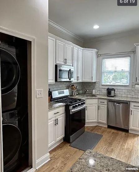 kitchen featuring stacked washer and dryer, white cabinetry, and stainless steel appliances