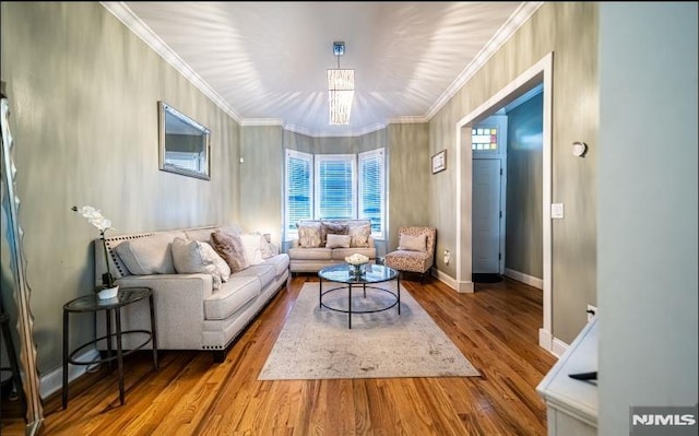 living room featuring hardwood / wood-style flooring, crown molding, and an inviting chandelier