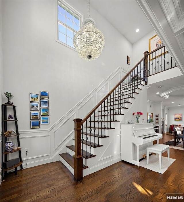 stairs featuring a towering ceiling, a chandelier, and wood-type flooring