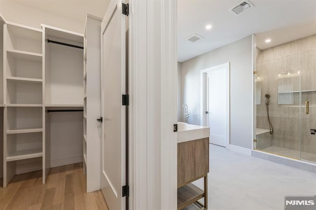 bathroom with hardwood / wood-style flooring, an enclosed shower, and vanity