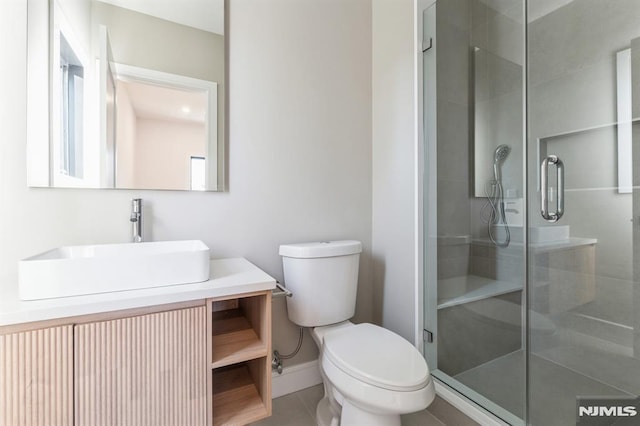 bathroom featuring toilet, tile patterned flooring, an enclosed shower, and vanity