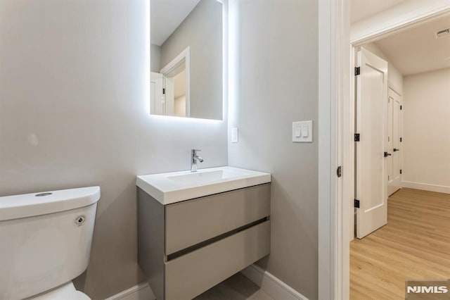 bathroom featuring toilet, hardwood / wood-style floors, and vanity