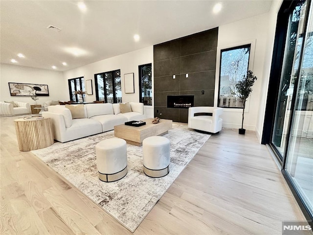 living room with light hardwood / wood-style flooring and a tiled fireplace