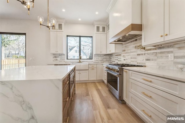 kitchen featuring sink, high end stainless steel range, white cabinets, and custom exhaust hood