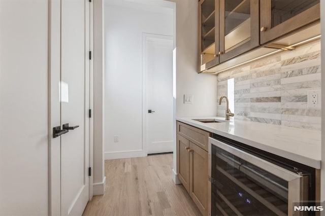 kitchen featuring tasteful backsplash, sink, beverage cooler, and light hardwood / wood-style flooring