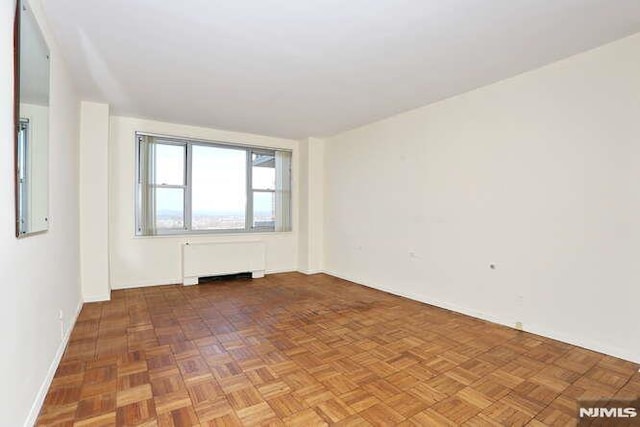 unfurnished room with radiator heating unit and parquet floors