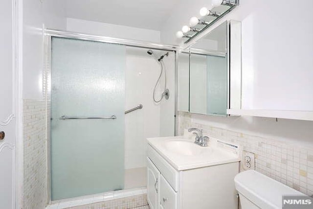 bathroom featuring toilet, a shower with door, and vanity