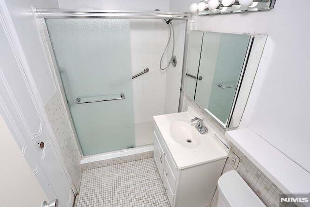 bathroom with toilet, tile patterned flooring, an enclosed shower, and vanity