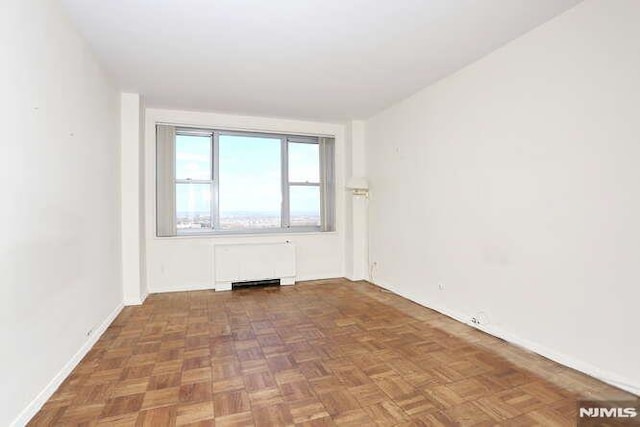 spare room with radiator heating unit and dark parquet floors