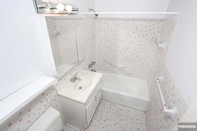 bathroom featuring washer / dryer, vanity, tile patterned flooring, and a tub to relax in