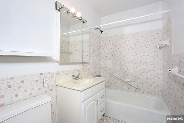 full bathroom featuring tile walls, tiled shower / bath combo, toilet, and vanity