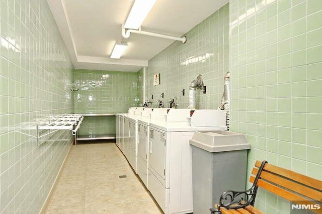 clothes washing area with washer and dryer and tile walls