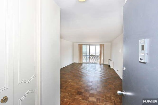 unfurnished living room with dark parquet flooring and radiator heating unit