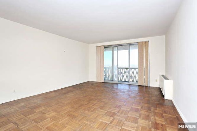 spare room with dark parquet flooring and radiator