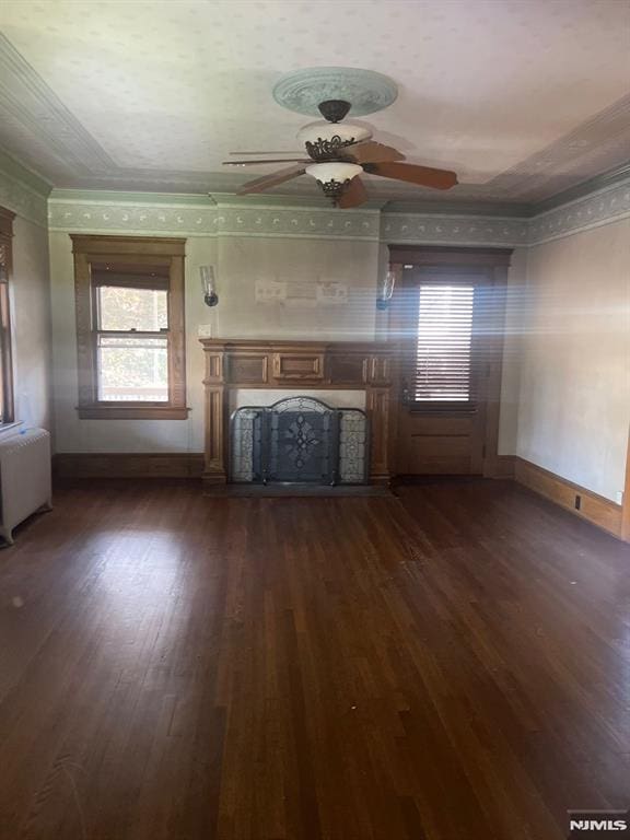 unfurnished living room featuring crown molding, dark wood-type flooring, ceiling fan, and radiator