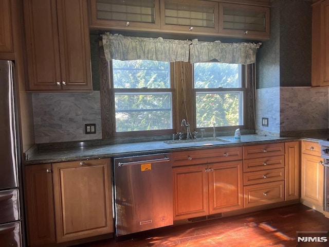 kitchen with appliances with stainless steel finishes, dark stone counters, decorative backsplash, and sink