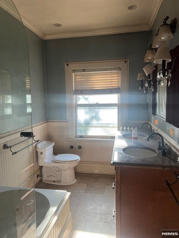 bathroom with toilet, a washtub, crown molding, and vanity