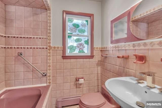 bathroom featuring tile walls, sink, a baseboard radiator, and a tub