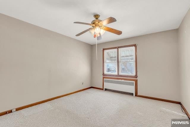 carpeted empty room featuring radiator and ceiling fan