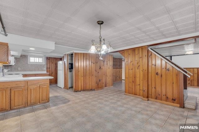 kitchen with white refrigerator, pendant lighting, and wood walls