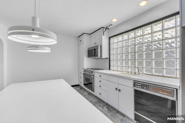 kitchen featuring pendant lighting, stainless steel appliances, sink, and white cabinets