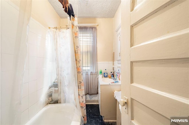 bathroom featuring vanity, shower / bath combination with curtain, and a textured ceiling