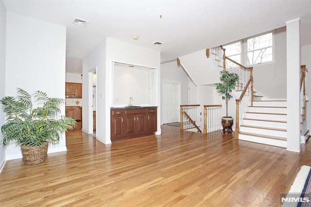 unfurnished living room with light hardwood / wood-style floors and sink