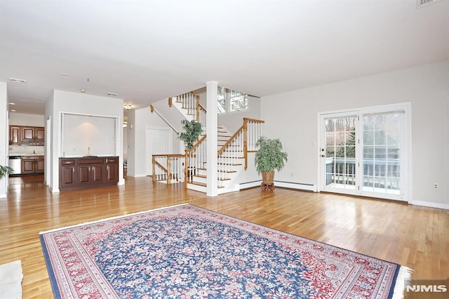 interior space featuring a baseboard radiator, a wealth of natural light, and light wood-type flooring